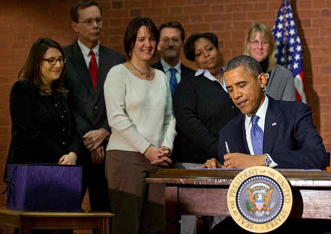 President Barack Obama signs the $1.1 trillion spending bill that funds the federal government through the end of September, in Washington, Friday, Jan. 17, 2014 at Jackson Place, a conference center near the White House. Obama signed the measure the day before federal funding was set to run out and was joined by aides who did much of the work negotiating it.