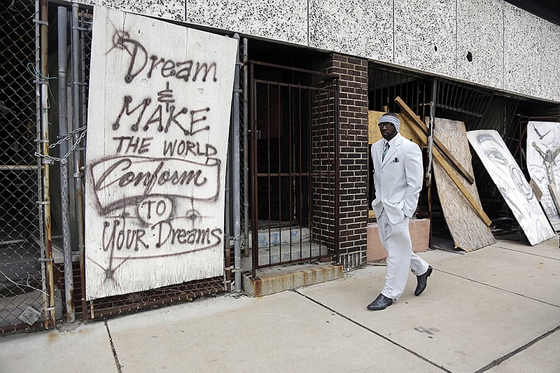 Melvin White, founder of the Beloved Streets of America project, walks past a boarded up building during a tour of Dr. Martin Luther King Jr. Drive in St. Louis. 