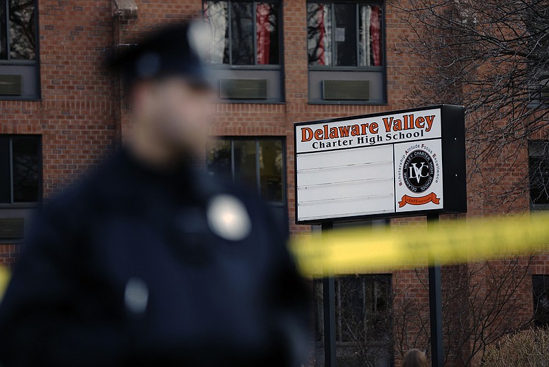 A policeman stands by caution tape at the Delaware Valley Charter School in Philadelphia. Police say two students have been shot at the Philadelphia high school.
