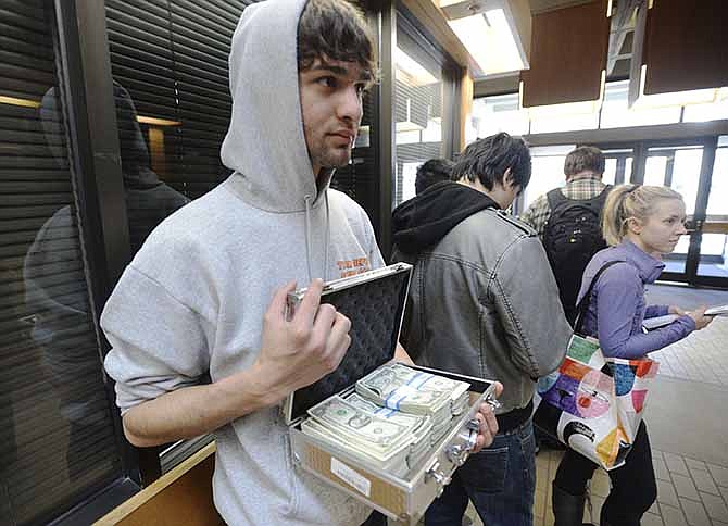 University of Utah student Luke Mughal holds a briefcase full of one-dollar bills as he waits in a long line to pay his tuition at the Student Services Building on the University of Utah campus in Salt Lake City, Utah Tuesday, Jan. 21, 2014. Mughal is paying his tuition in one-dollar bills to protest the high cost of tuition. 
