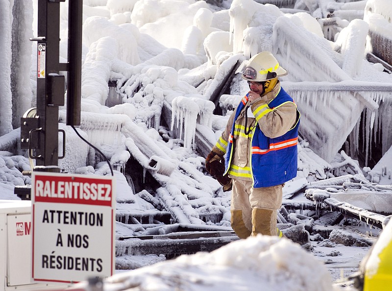 An emergency worker walks past a sign that reads "Look out for our residents" as they search through the icy rubble of a fire that destroyed a seniors' residence Friday, Jan. 24, 2014, in L'Isle-Verte, Quebec. Five people are confirmed dead and 30 people are still missing, while with cause of Thursday morning's blaze is unclear police said.