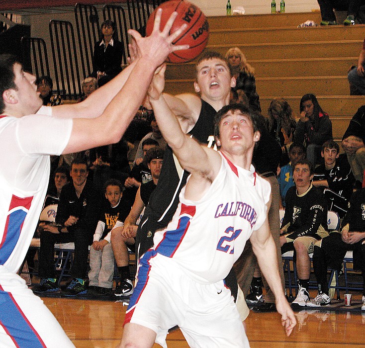 From left, California junior Damon Shaw and senior Jerry Lutz (21) scramble for the rebound during the varsity game against Versailles Friday night at California. 