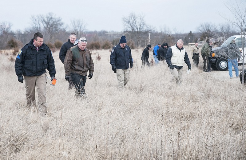 Officers from the Holts Summit and Jefferson City police departments as well as the Callaway County Sheriff's Office and Missouri State Highway Patrol search a grassy field for evidence behind the Holts Summit Exxon Mobile on the 100 block of East Simon Boulevard on Thursday after a deceased woman was discovered there at 11:28 a.m.