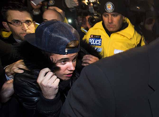 Canadian musician Justin Bieber is swarmed by media and police officers as he turns himself in to city police for an expected assault charge, in Toronto, on Wednesday, Jan. 29, 2014. A police official said the charge has to do with an alleged assault on a limo driver in December. 