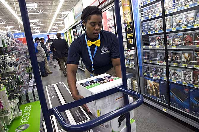 In this Wednesday, Dec. 4, 2013, photo, Tracey Anderson, 26, re-stocks X-Box sets on opening day of a new Wal-Mart on Georgia Avenue Northwest in Washington.