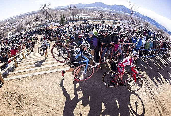 In this image taken with a fisheye lens on Jan. 12, 2014, and released by USA Cycling, Katie Compton, center, carries her bike up an incline during the women's elite division at the USA Cyling cyclo-cross national championship in Boulder Colo. unique blend of road racing and mountain biking has been booming in Europe for decades, but only in the last five years has it caught fire in the U.S., where thousands of riders are turning out for races on courses built everywhere from farm fields to urban parks.