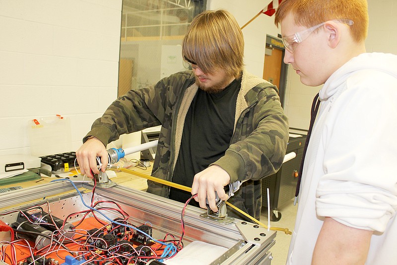 Fulton High School sophomore Alex Zajdel, left, and sophomore Miles Johnson tinker with a robot in class Friday. The robotics club, which builds a robot to perform specific types of tasks in competition, has already utilized the new equipment from the fab lab. The blue bracket, seen just below Zajdel's wrist, was made with a new 3D printer.