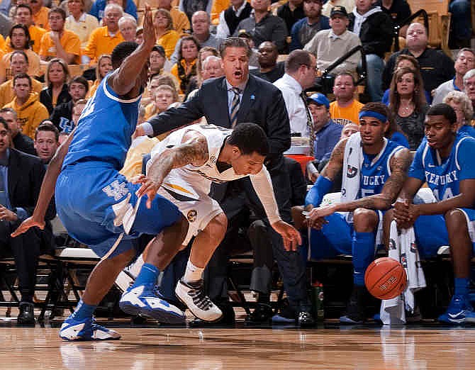 Missouri's Jabari Brown, right, looses the ball in front of the Kentucky bench as Kentucky's Alex Poythress, left, defends during the first half of an NCAA college basketball game Saturday, Feb. 1, 2014, in Columbia, Mo.