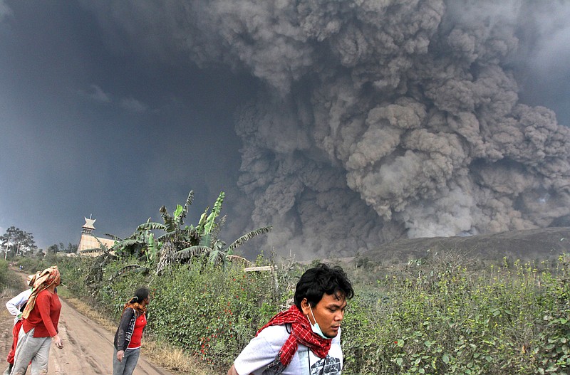 Villagers and a journalist prepare to flee as Mount Sinabung releases pyroclastic flows during an eruption in Namantaran, North Sumatra, Indonesia, on Saturday. The rumbling volcano in western Indonesia has unleashed fresh clouds of searing gas, killing at least 16 people.