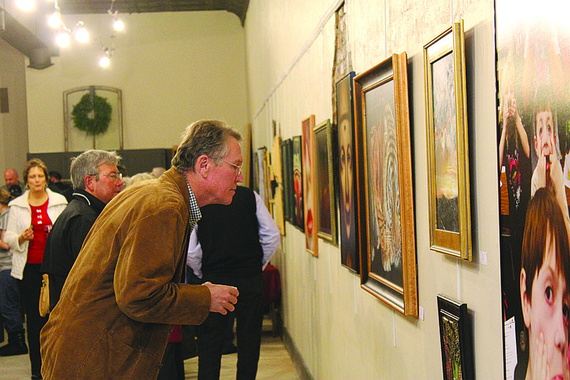 A man observes a piece of artwork during the sneak preview of the Art House in downtown Fulton in December. Its grand opening event will take place today.