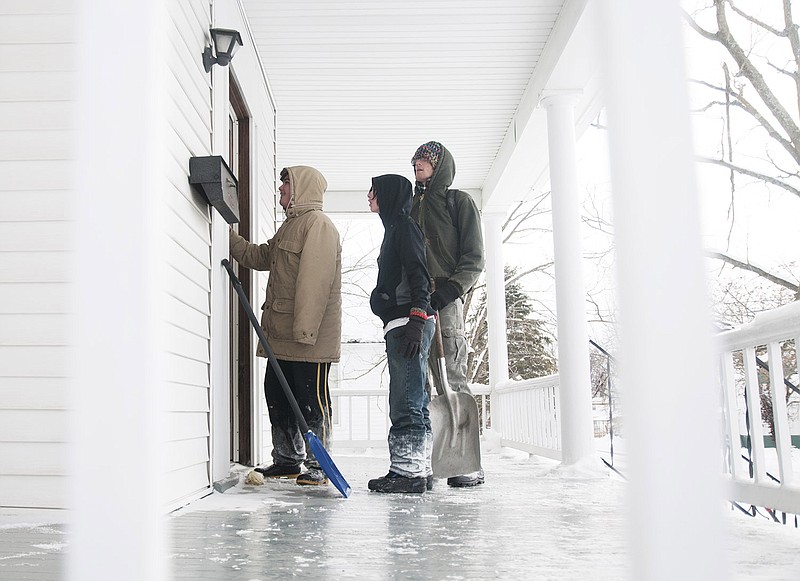 Dakota Adams, 13, of Fulton knocks on the door of a home on Bluff Street to receive payment after he and his friends, Aaron Popchoke, 13, Isaac Schneller, 22, and Savannah De Leal, 14, (not pictured) shoveled sidewalk and around a parked car. They were paid $20 total.