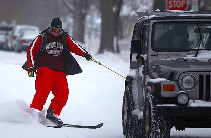 MSU student Marcus Hibbard, left, skis through the streets behind a Jeep in Springfield on Tuesday.