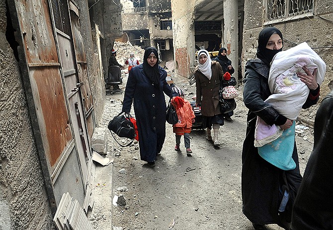 Residents of the besieged Yarmouk Palestinian refugee camp carry their belongings as they flee the camp Tuesday, on the southern edge of the Syrian capital Damascus, Syria.