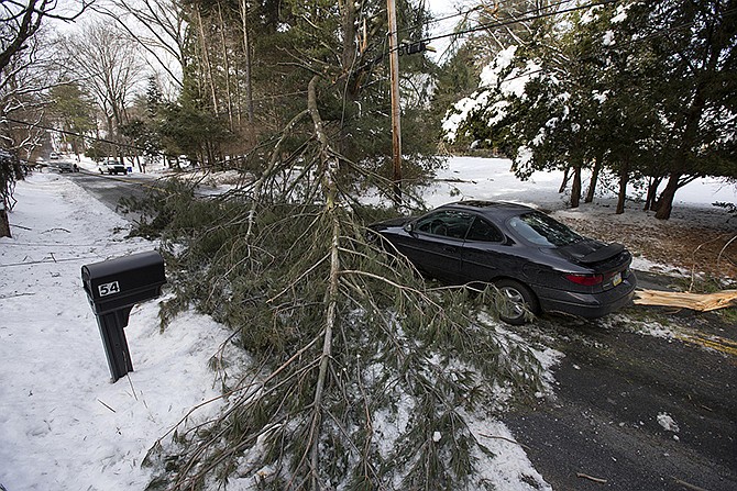 An abandoned car and a tree limb that took out a utility line block a road on Thursday in the aftermath of a winter storm in Media, Pa. Thousands of utility workers are trying to restore power knocked out by an ice storm that left more than 849,000 Pennsylvania households and businesses without electricity, but officials say toppling trees are still causing fresh outages.