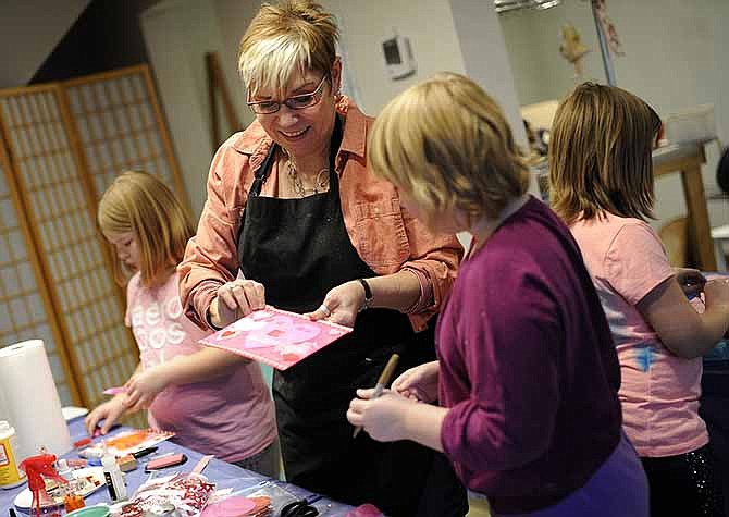 Art instructor Charlotte Middleton helps a group of young artists as they work on their mixed media Valentine's Day collages during a recent Kids' Art Workshop at The Village Art Studio in historic Warwick Village in Jefferson City.