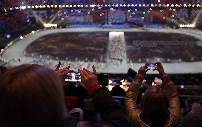 In this Friday, Feb. 7, 2014, file photo, a spectator takes a video of the opening ceremony on her mobile phone at the 2014 Winter Olympics in Sochi, Russia.