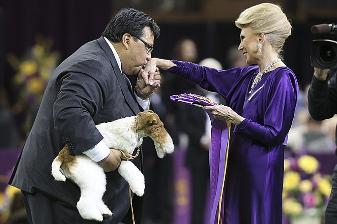 Sky, a wire fox terrier, is held Tuesday as his handler Gabriel Rangel kisses the hand of judge Betty Regina Leininger after winning best of show during the Westminster Kennel Club dog show.