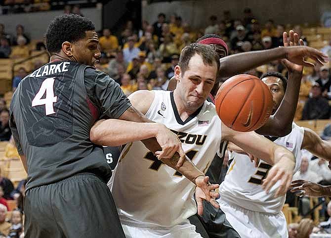 Missouri's Ryan Rosburg, center, battles Arkansas' Coty Clarke, left, for a rebound during the first half of an NCAA college basketball game Thursday, Feb. 13, 2014, in Columbia, Mo.