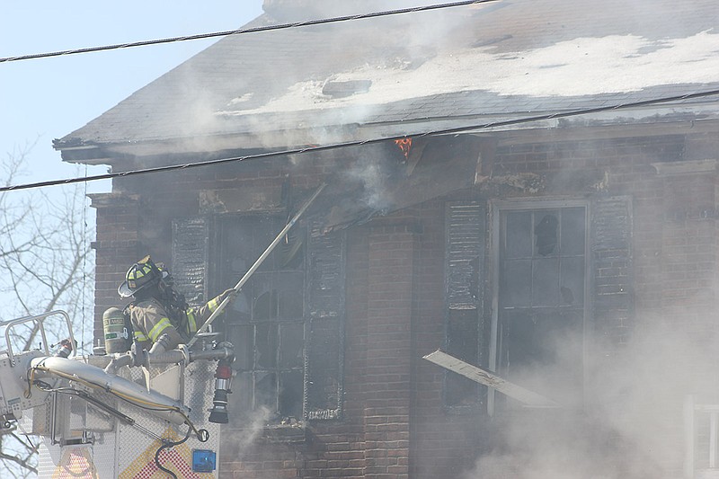 A Fulton firefighter pulls down part of the gutter to reveal another hot spot in the attic space. Chief Dean Buffington said crews would likely spend most of the afternoon chasing down such hot spots.