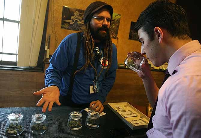 Customer Paxton Berlanga, of Indiana, right, smells a strain of marijuana, while being helped by employee Billy Archilla, inside the retail marijuana shop at 3D Cannabis Center, in Denver, Friday Feb. 14, 2014.
