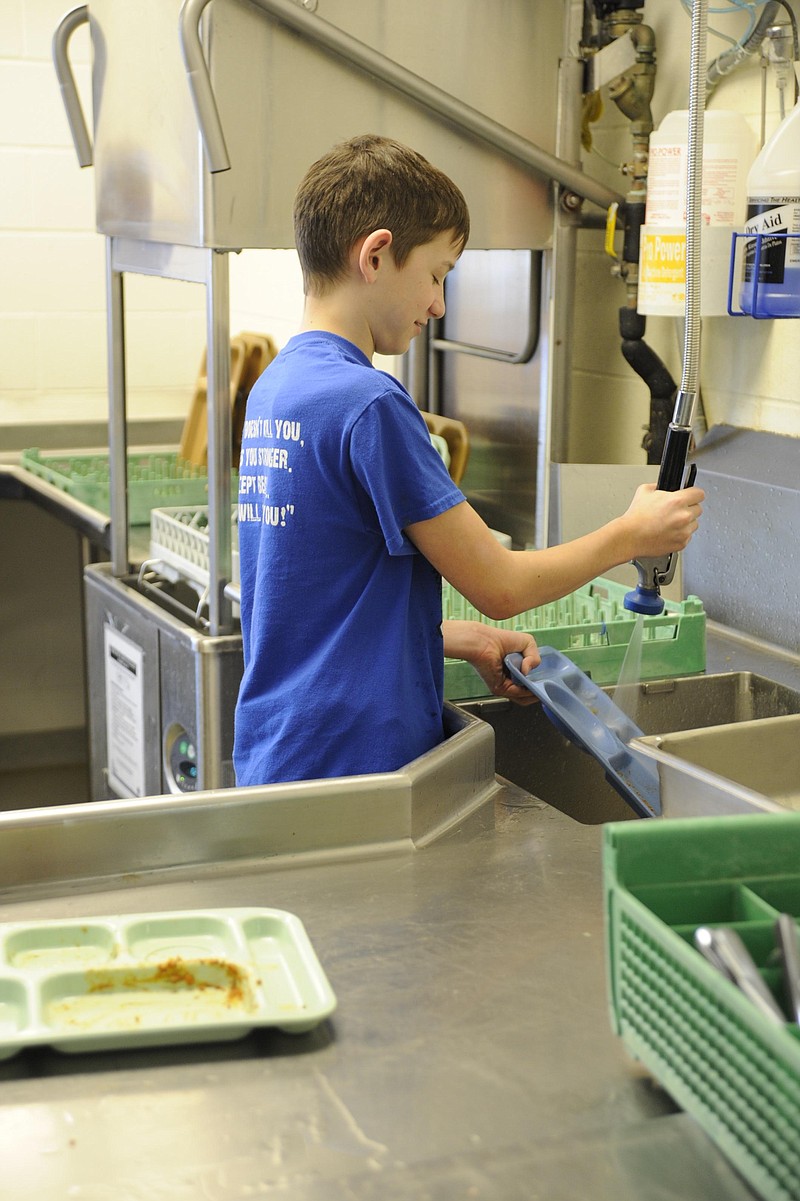 Austin Rohe, 13, rinses trays and prepares them for the wash at the Outlaw Baseball program's fourth annual spaghetti dinner and silent auction Sunday in Russellville. Democrat photo/Michelle Brooks