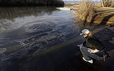Amy Adams, North Carolina campaign coordinator with Appalachian Voices, dips her hand into the Dan River on Feb. 5 in Danville, Va. as signs of coal ash appear in the river. Duke Energy estimates up to 82,000 tons of ash has been released from a break in a 48-inch storm water pipe at the Dan River Power Plant in Eden N.C. Over the last year, environmental groups have tried three times to use the federal Clean Water Act to force Duke Energy to clear out leaky coal ash dumps.