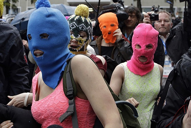 Russian punk group Pussy Riot members Nadezhda Tolokonnikova, in the blue balaclava, and Maria Alekhina, in the pink balaclava, make their way through a crowd after they were released from a police station Tuesday in Adler, Russia.