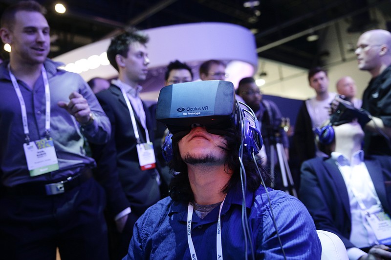 In this Jan. 7, 2014 file photo, show attendees play a video game wearing Oculus Rift virtual reality headsets at the Intel booth at the International Consumer Electronics Show(CES), in Las Vegas. Filmmaker Danfung Dennis' latest project: a virtual reality documentary, "Zero Point," will be the first movie released for the Oculus Rift, a VR headset that provides an immersive 110-degree field of view with high-definition stereoscopic 3D and low-latency head tracking. 