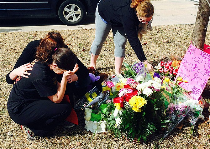 Stacey Owens, front left, mother of Hailey Owens, is consoled Thursday by Sara Wells, left, as family member Teri Nord arranges flowers left by well wishers near the site where the 10-year-old girl was abducted just blocks from her Springfield home.