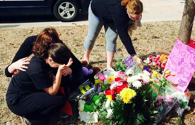 Stacey Barfield, mother of Hailey Owens, foreground left, is consoled by Sara Wells, as family member Teri Nord, right, arranges flowers left by well wishers Feb. 20, 2014 near the site where the 10-year-old girl was abducted just blocks from her Springfield, Mo., home. Prosecutors charged Craig Michael Wood with first-degree murder, kidnapping and armed criminal action in the girl's death. Prosecutors say the fourth-grader's body was found stuffed in two trash bags inside plastic storage containers in the basement of Wood's Springfield home.