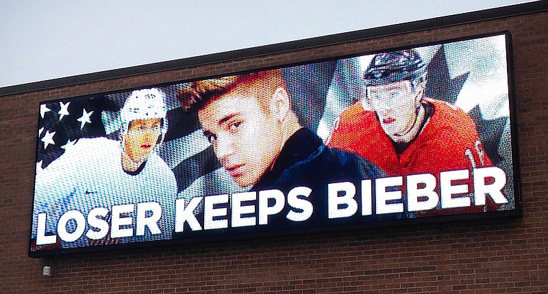 In this photo provided by Command Transportation, an electronic billboard displays pop star Justin Bieber, center, sandwiched by Chicago Blackhawks stars Patrick Kane, left, and Jonathan Toews outside the Skokie, Ill., based freight company. Kane, who plays for Team USA and Toews for Team Canada, played against each other in a men's semifinal ice hockey game at the 2014 Winter Olympics, Friday, Feb. 21, 2014. Canada won 1-0 to advance to the gold medal game. 