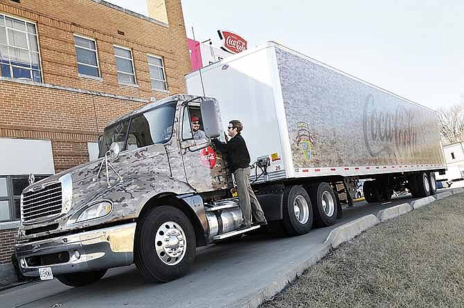 Jake Vogel talks to delivery driver Jason Bittle as he moves one of the new trucks at Coca-Cola plant in Jefferson City, Mo. The company has updated their distribution process and will begin using some new trucks, including this camouflaged semi.