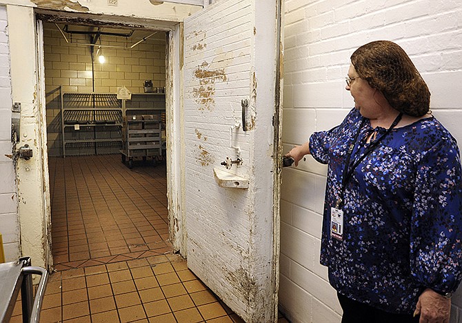 Laura Crandall of Dietic Services at Fulton State Hospital shows the large walk-in cooler that still has a wooden door and frame that has been painted numerous times. The House pitched a new plan for the Fulton state hospital that would cost $47M a year for five years. 