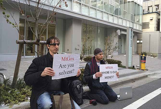 Bitcoin trader Kolin Burges, right, of London and American Aaron (only his first name was given) hold protest signs as they conduct a sit-in in front of the office tower housing Mt. Gox in Tokyo Tuesday, Feb. 25, 2014. The website of major Bitcoin exchange Mt. Gox is offline Tuesday amid reports it suffered a debilitating theft, a new setback for efforts to gain legitimacy for the virtual currency. The URL of Tokyo-based Mt. Gox was returning a blank page. The disappearance of the site follows the resignation Sunday of Mt. Gox CEO Mark Karpeles from the board of the Bitcoin Foundation, a group seeking legitimacy for the currency. Burgess said he had picketed the building since Feb. 14 after flying in from London, hoping to get back $320,000 he has tied up with Mt Gox. 