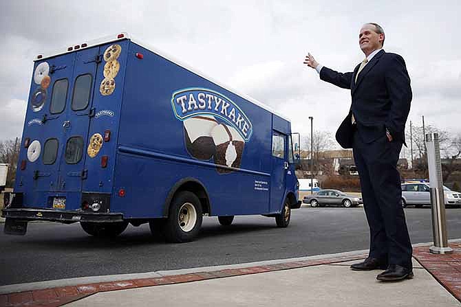 Tastykake President Paul Ridder waves to trucks headed off to make deliveries to first responders and charities around the city, as Tastykake marks its 100th anniversary Tuesday, Feb. 25, 2014, in Philadelphia. Tastykake made 100 cakes on its first day of business in 1914. Now, it produces nearly 5 million cakes, doughnuts, cookies and pies each day.