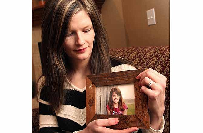 Erin Petersen holds a photo of her niece, Hailey Owens, Wednesday Feb. 19, 2014. A middle-school football coach has been jailed on suspicion of first-degree murder in the abduction and death of a 10-year-old girl in southwest Missouri, police said Wednesday. 