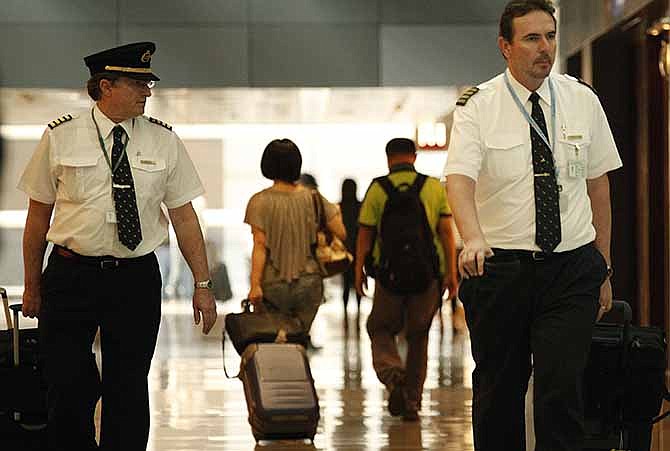 In this Nov. 30, 2011, file photo, two pilots from Cathay Pacific walk in the Hong Kong International Airport in Hong Kong. The U.S. airline industry will need to hire 1,900 to 4,500 new pilots annually over the next 10 years due to an expected surge in retirements of pilots reaching age 65 and increased demand for air travel, the Government Accountability Office said in the report obtained late Thursday, Feb. 27, 2014.
