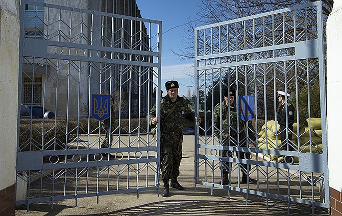 A Ukrainian soldier closes the naval base headquarter gate in the town of Novo-Ozerne. For years, the little Crimean town was closed off from the rest of the world, a secretive community, at the edge of a key Soviet naval base, sealed by roadblocks and armed guards. The little forgotten town is now sharply divided, torn between those who welcomed the arrival here over the weekend of dozens of Russian soldiers wearing unmarked uniforms, and those who back the Ukrainians and are refusing to surrender their weapons.