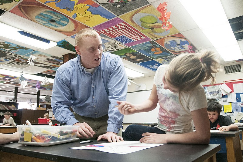 Dustin Haley, South Callaway elementary and middle school art teacher, gives third grader Lacey Mathews-Honamand advice on her artwork Wednesday during class. The students were learning symmetry by folding a pieces of paper and drawing aliens.