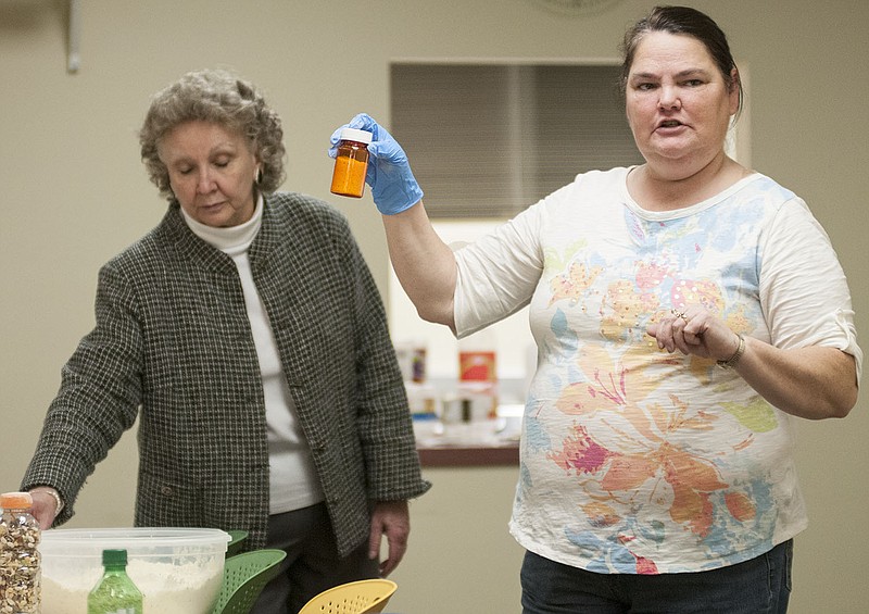 Mylene Dunn (left), Callaway County environmental public health specialist, shows a group of people a medicine jar filled with dried soup during the "Storing Food for Emergencies" demonstration Thursday night at the Callaway County Library.