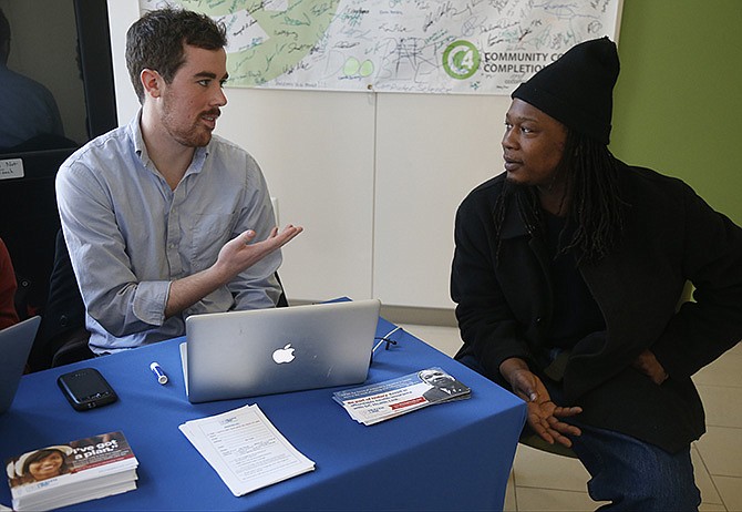 David Bransfield, a state outreach coordinator for Young Invincibles, a group which supports President Barack Obama's health care law, talks with student Philippe Komongnan, 27, who is in the process of signing up for health care, at the University of the District of Columbia in Washington, Thursday, Jan. 30, 2014. An army of workers and volunteers has fanned out around the country trying to enroll young and healthy people in health insurance now available through Obama's signature law.