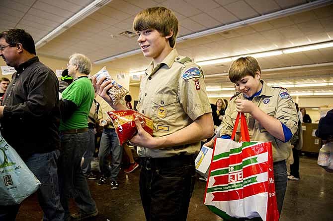 Troop 5 Scouts Kourtnie Schulte, center, and Ben Dudenhoeffer, right, carry donated food to the sorting area Saturday morning during the Scouting for Food drive.