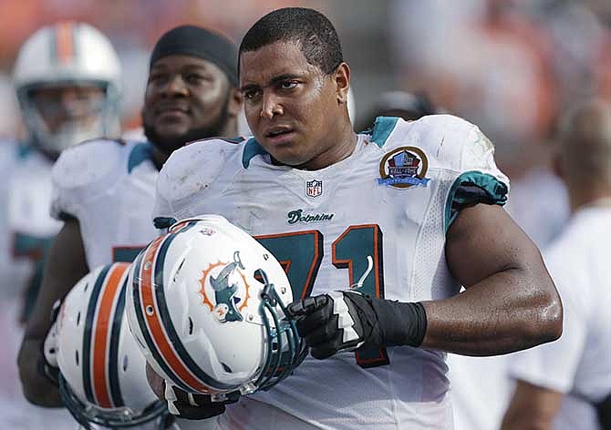 In this Dec. 16, 2012, photo, Miami Dolphins tackle Jonathan Martin (71) stands on the sidelines during the Dolphins' NFL football game against the Jacksonville Jaguars in Miami. Martin, the offensive tackle at the center of the Dolphins' bullying scandal, has been traded to the San Francisco 49ers. The Dolphins announced the deal Tuesday night, March 11, 2014, on the first day of NFL free agency. Martin's move cross country brings him back to the Bay Area to be reunited with his former Stanford coach, Jim Harbaugh.
