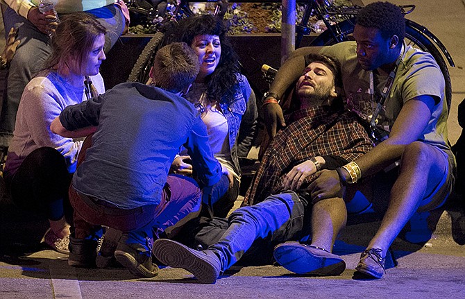 Bystanders and paramedics tend to a person who was struck by a vehicle on Red River Street in downtown Austin, Texas, at SXSW.  Police say a man and woman were killed after a suspected drunken driver fleeing from arrest crashed through barricades set up for the South By Southwest festival and struck the pair and others on a crowded street. 