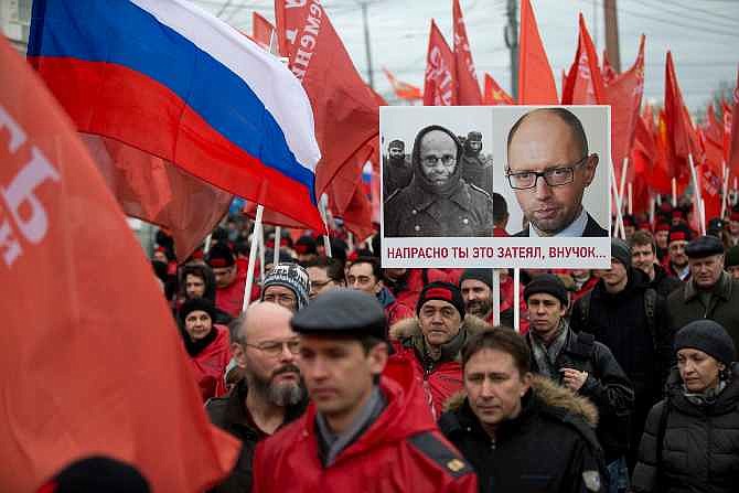 Demonstrators march in support of Kremlin-backed plans for the Ukrainian province of Crimea to break away and merge with Russia, in Moscow, Saturday, March 15, 2014. Large rival marches have taken place in Moscow over Kremlin-backed plans for Ukraine's province of Crimea to break away and merge with Russia. A poster depicts photos of WWII German prisoner of war and Ukrainian prime minister Arseniy Atsenyuk, and says "Your project is doomed, grandson..." 