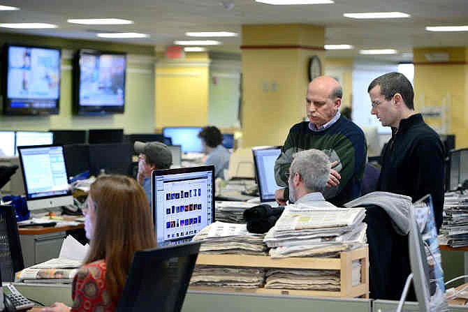 Cliff Schechtman, Portland Press Herald executive editor, left, and Steve Greenlee, managing editor, right, talk with Brian Robitaille, seated, on the copy desk/slot to discuss the next day's front page in Portland, Maine on Tuesday, March 11, 2014.