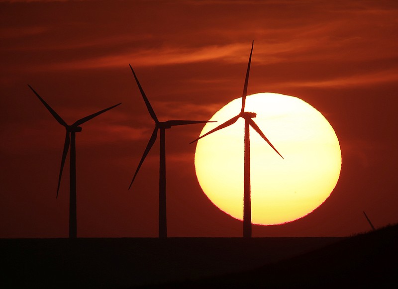 Wind turbines are silhouetted by the setting sun as they produce electricity near Beaumont, Kan. The plains of Kansas could be a treasure trove in the nation's growing effort to harness clean energy. But a major proposal to move wind-generated electricity from Kansas to the East is running into a roadblock: Farmers who don't want high-power transmission lines on their land. 