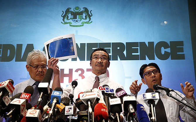 Malaysian acting Transport Minister Hishamuddin Hussein, center, shows maps of South Corridor and North Corridor of the search and rescue on Monday with director general of the Malaysian Department of Civil Aviation, Azharuddin Abdul Rahman, right, and Malaysian Deputy Foreign Minister Hamzah Zainudin during a press conference at a hotel next to the Kuala Lumpur International Airport, in Sepang, Malaysia.