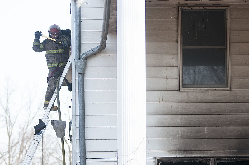 A South Callaway firefighter tears off the siding of a Readsville home after it was destroyed in a fire Tuesday afternoon. No one was injured in the fire.