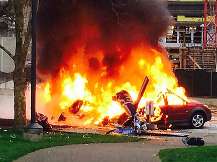 In this photo provided by KOMO-TV, a car burns at the scene of a helicopter crash outside the KOMO-TV studios near the space needle in Seattle today. The station says the helicopter was apparently coming in for a landing on its rooftop this morning when it possibly hit the side of the building and went down, hitting several vehicles on Broad Street. 